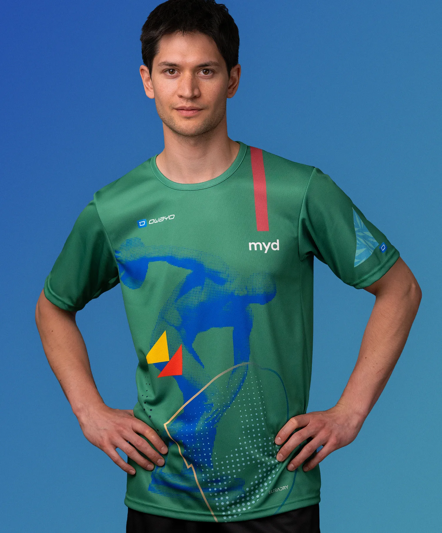 En mann i en grønn, tilpasset sportskjorte fra owayo med et blått, gult og rødt grafisk design og ordet 'myd' på brystet.